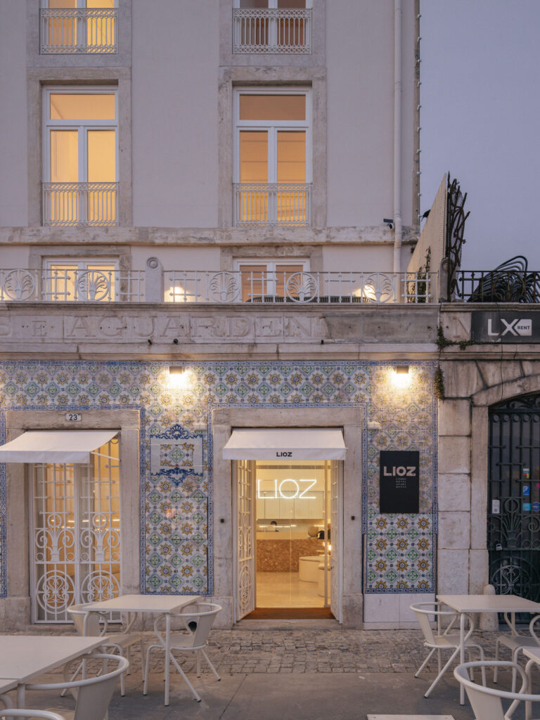 White tables and chairs on the cobbles outside the tiled front door at dusk