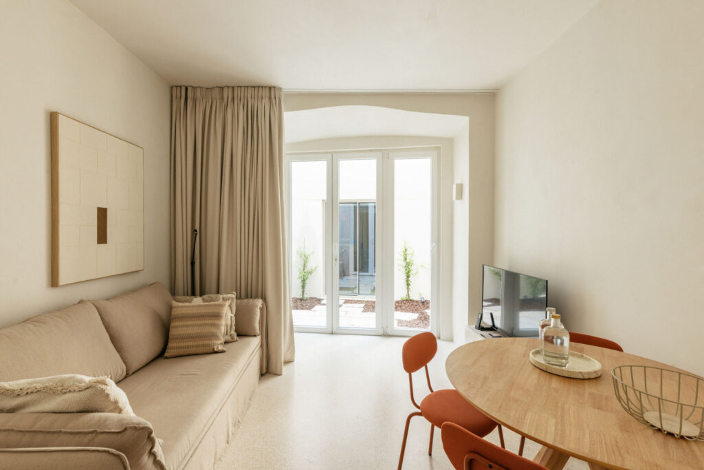 Living room with sofa, round dining table and patio doors – LIOZ Lisboa