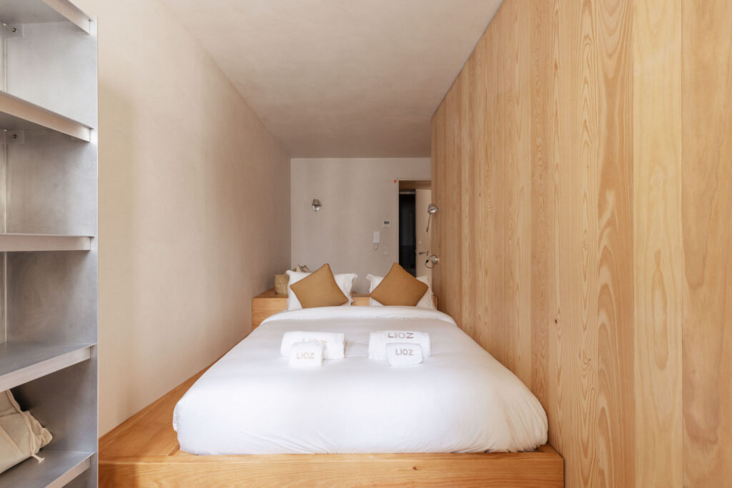 Bedroom with LIOZ towels on a white double bed – LIOZ Lisboa