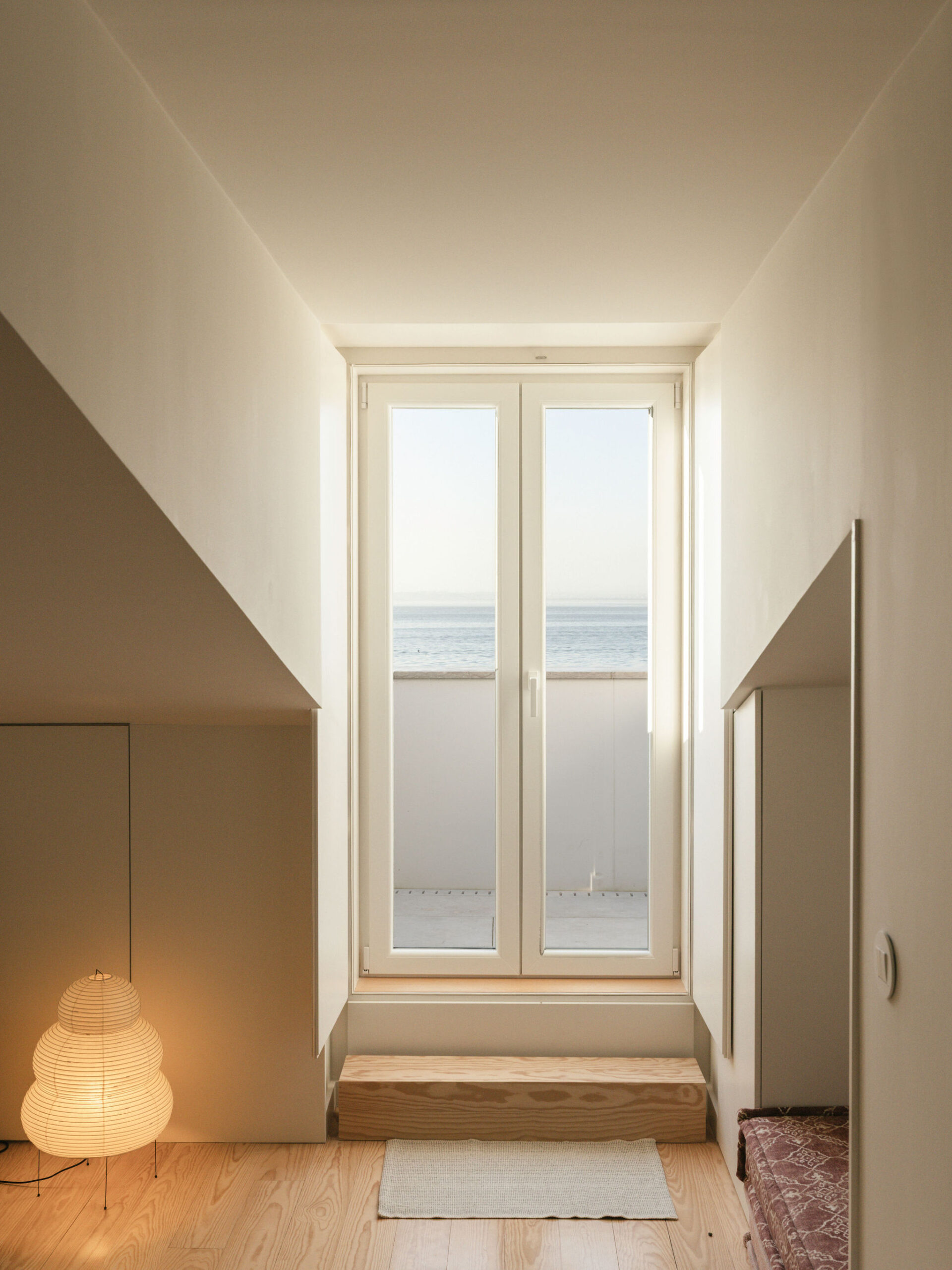 A tall window at the end of a quiet room, with soft daylight