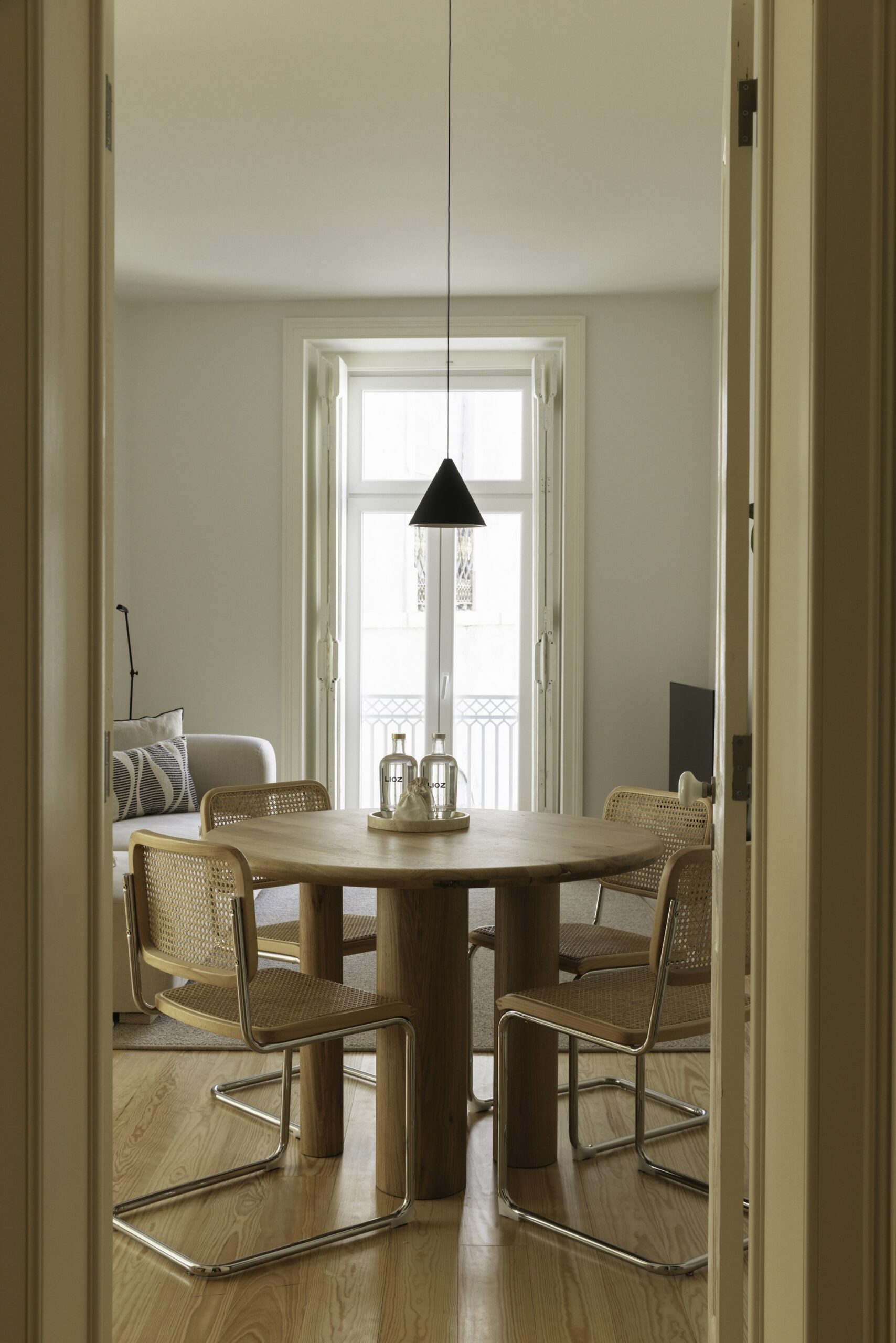 A dining room seen through an open door, with a round table and cane chairs