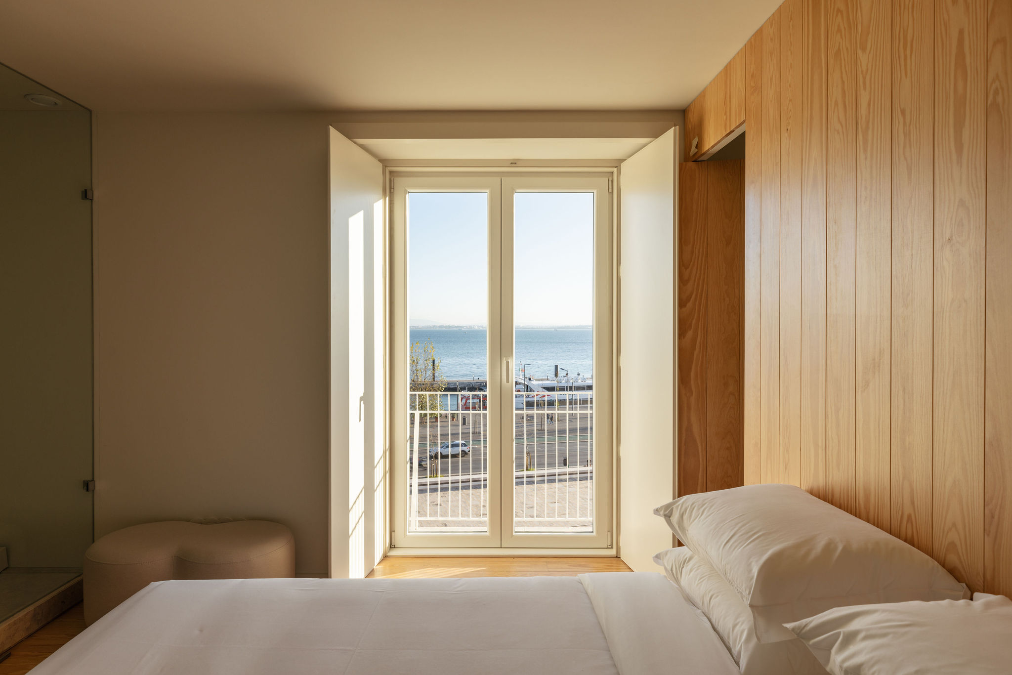 A bedroom facing a tall window, with the river beyond