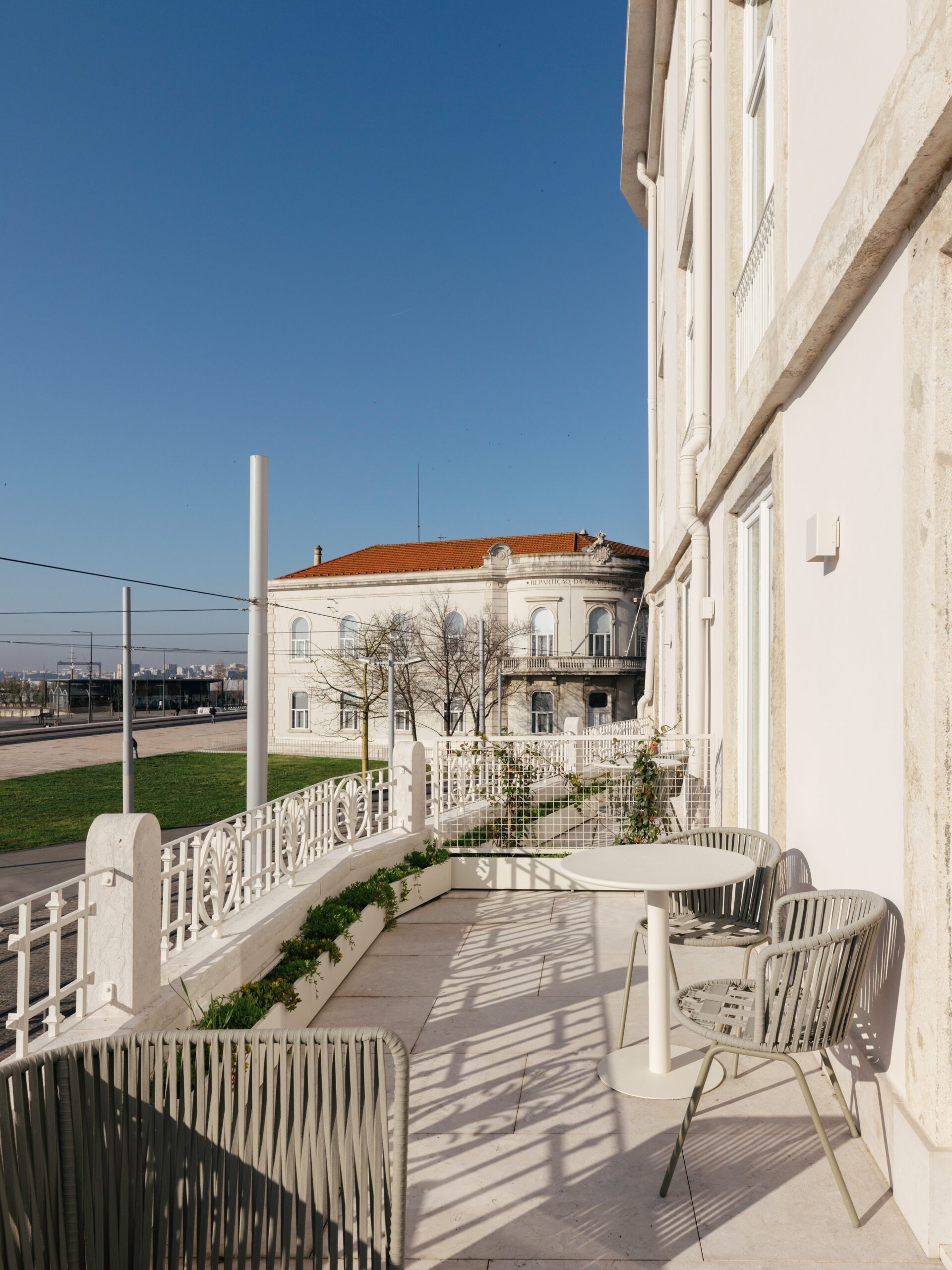 A terrace with a table and chairs, a white balustrade and a patio below